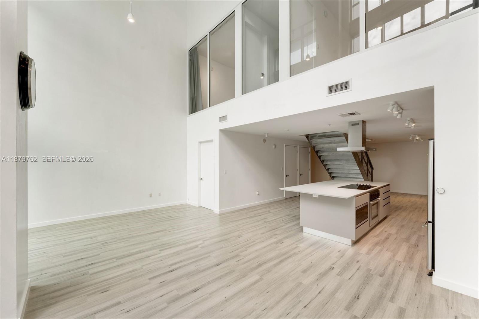 A modern, open-concept living area features high ceilings, light wood flooring, and a kitchen island — 3301 NE 1st Ave # M0501, Miami FL 33137, MIAMI, FL