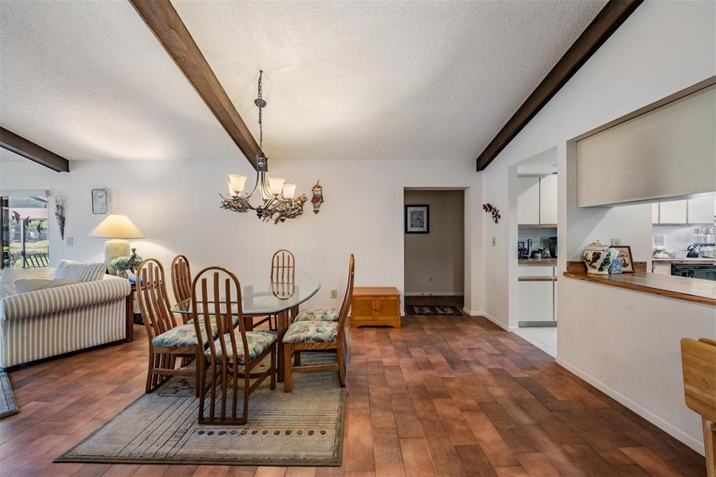 A dining area with a glass table, wooden chairs, and exposed ceiling beams — 3505 TARPON WOODS BOULEVARD UNIT N401, PALM HARBOR, FL