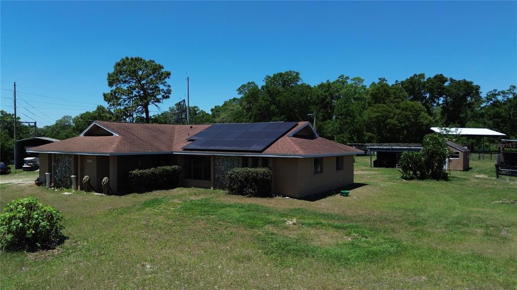 A single-story house with a brown shingled roof and solar panels sits on a grassy lot — 10631 W HIGHWAY 40, OCALA, FL