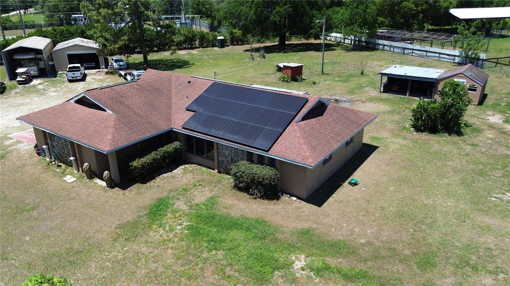 An aerial view of a house with solar panels, a detached garage, and outbuildings — 10631 W HIGHWAY 40, OCALA, FL