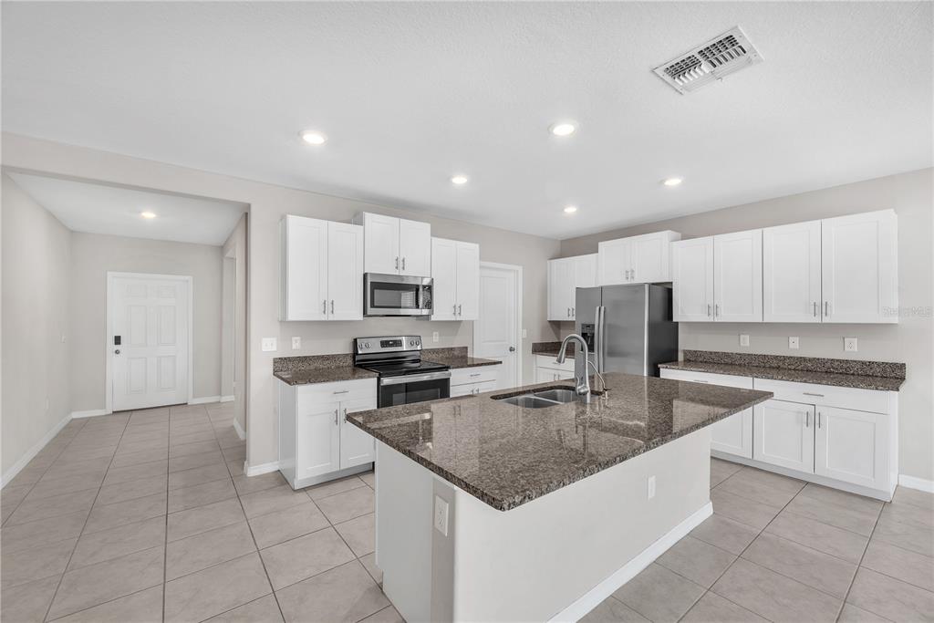 A kitchen with white cabinets, granite countertops, a central island, and tile flooring — 1846 SILVER STAR PLACE, RUSKIN, FL