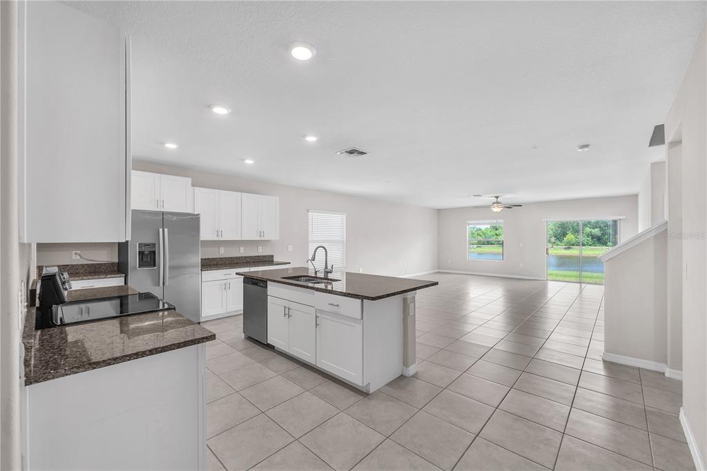 A kitchen with white cabinets and granite countertops opens to a spacious living area — 1846 SILVER STAR PLACE, RUSKIN, FL
