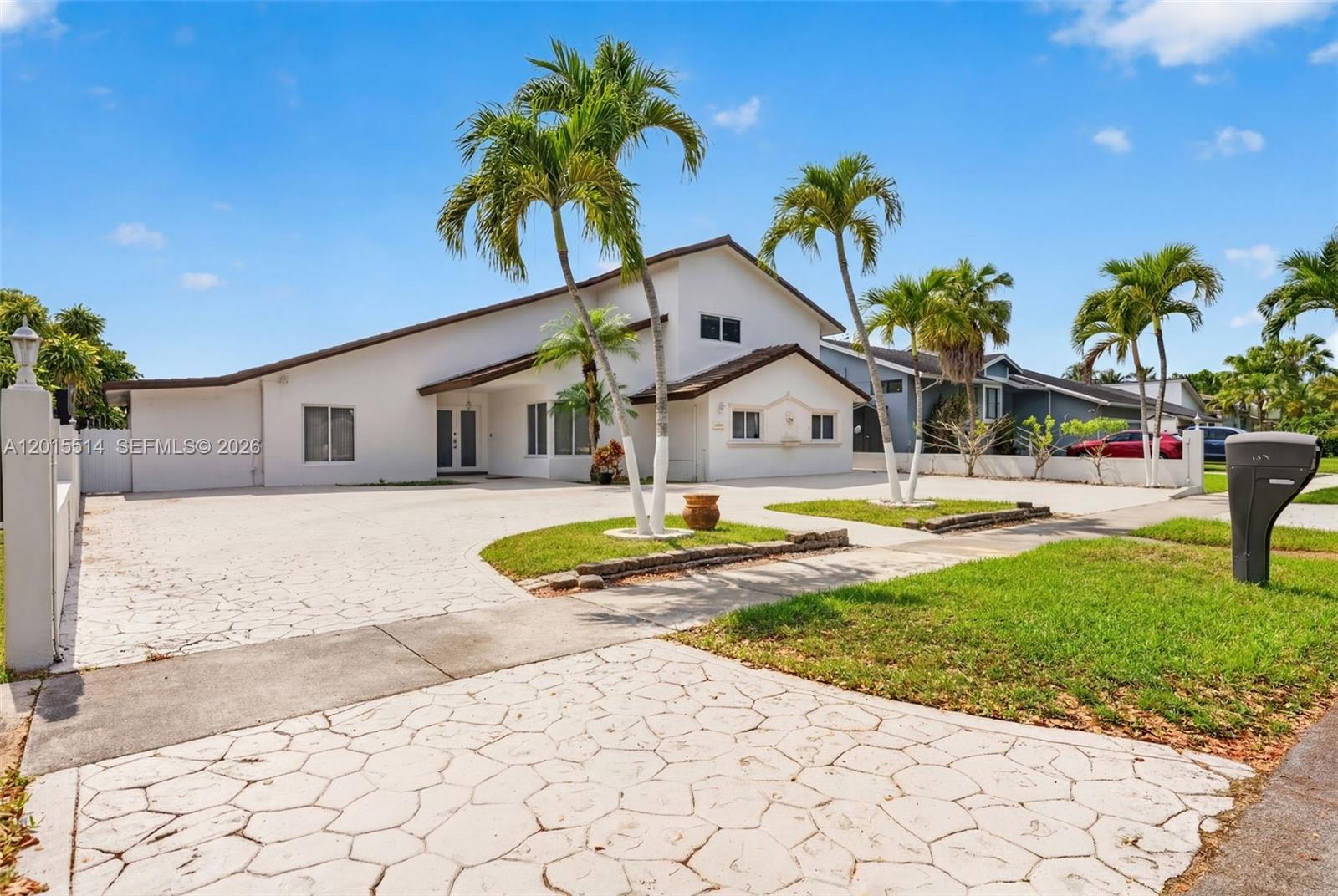 A white two-story house features a large paved driveway and several palm trees — 10934 SW 137th Ct, Miami FL 33186, MIAMI, FL