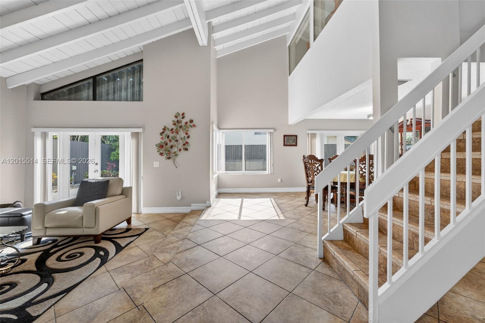 A living and dining area features vaulted ceilings, tile flooring, and a staircase — 10934 SW 137th Ct, Miami FL 33186, MIAMI, FL