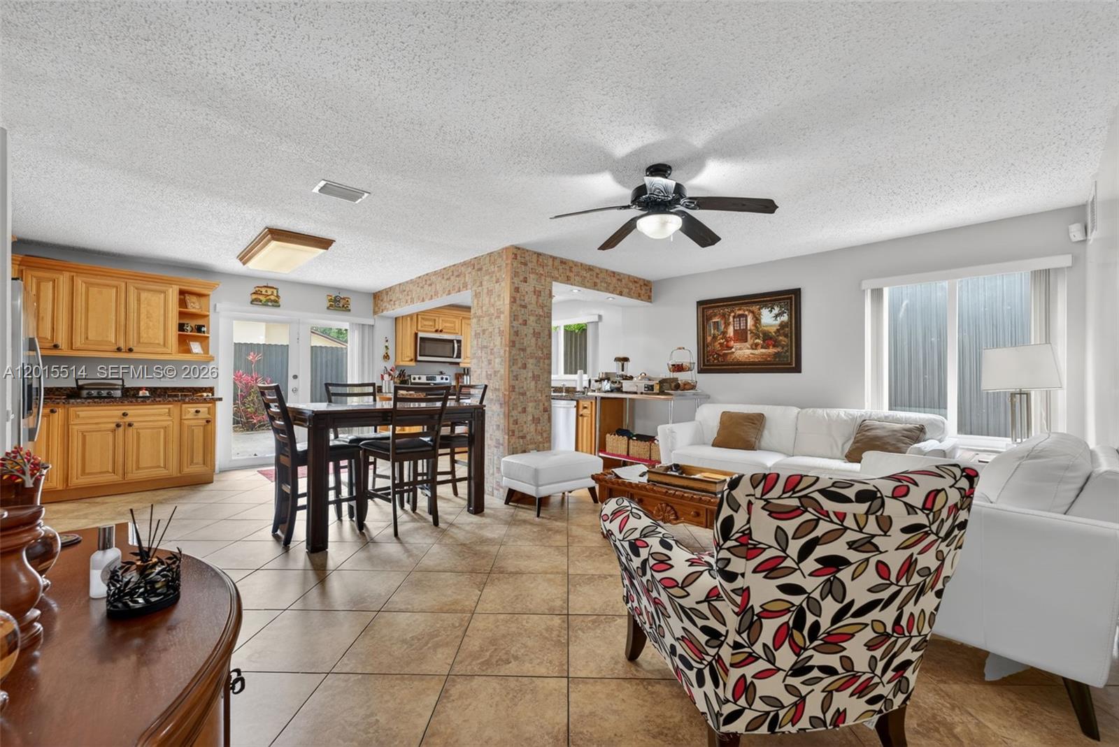An open-concept living and dining area features tile floors, light wood cabinets, and a ceiling fan — 10934 SW 137th Ct, Miami FL 33186, MIAMI, FL