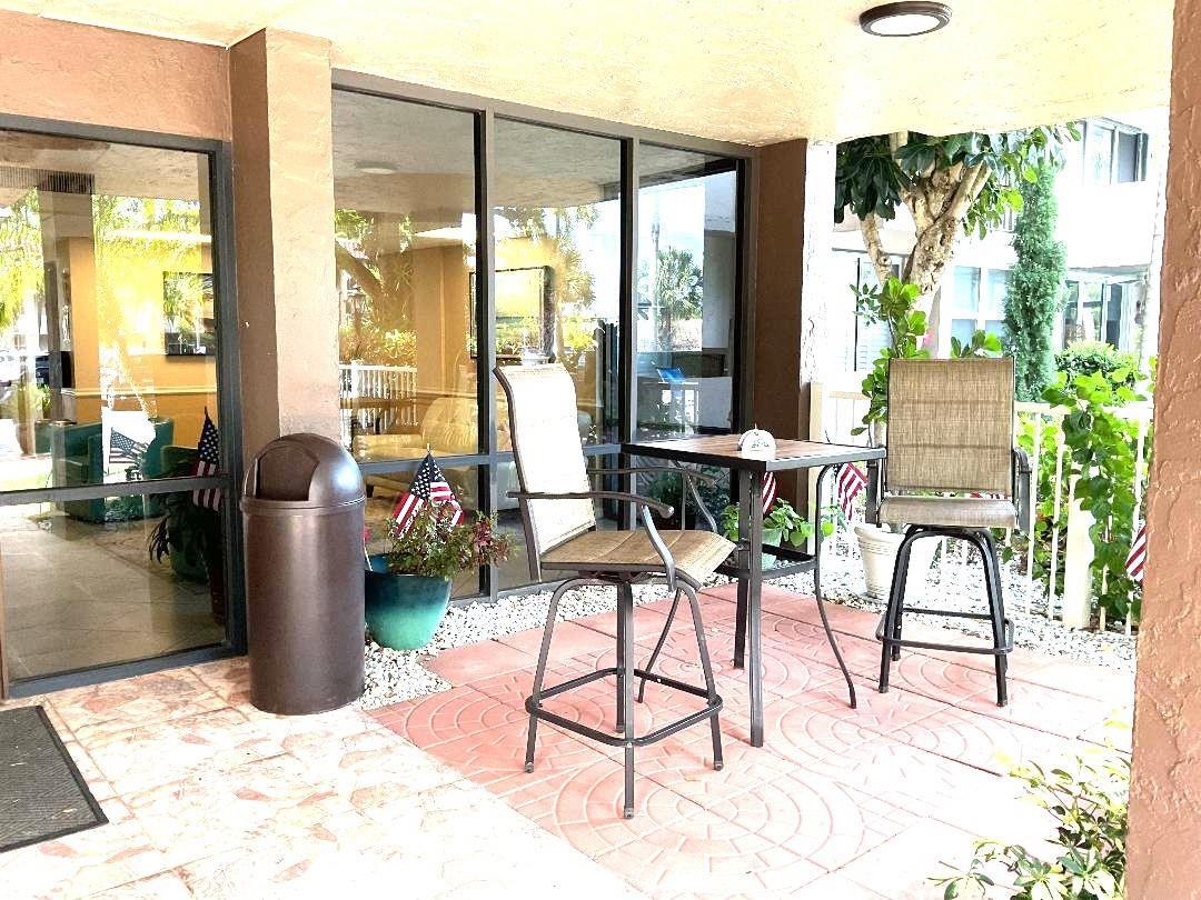 A patio features a small table with two chairs, a trash receptacle, and glass doors — 777 S Federal Highway, Pompano Beach FL 33062, POMPANO BEACH, FL