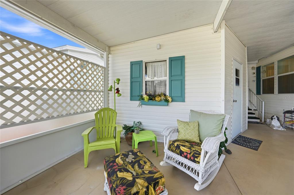 A covered patio features a white wicker rocking chair, a lime green chair, and lattice walls — 600 WOODWYN COURT, NORTH PORT, FL