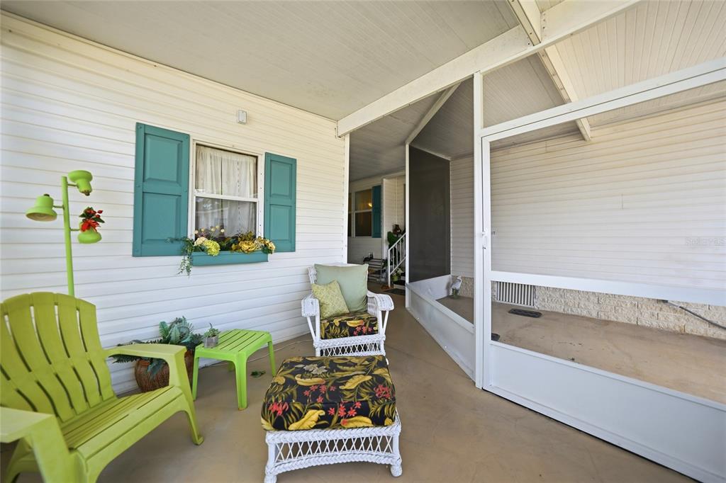 A covered patio features white siding, a screened-in area, and lime green outdoor furniture — 600 WOODWYN COURT, NORTH PORT, FL