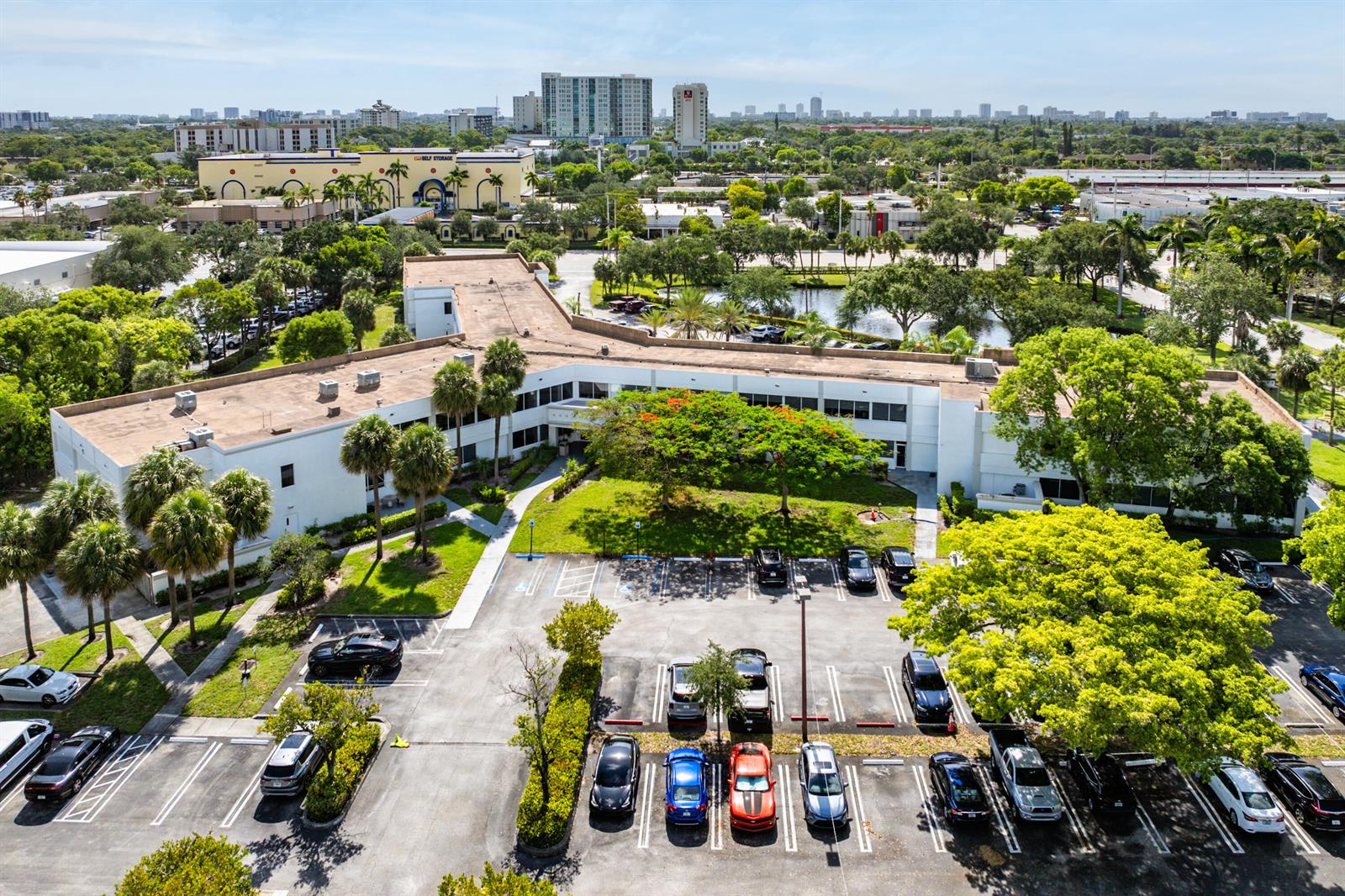 An aerial view shows a low-rise office building with a parking lot and surrounding trees — 555 SW 12th Avenue, Pompano Beach FL 33069, POMPANO BEACH, FL