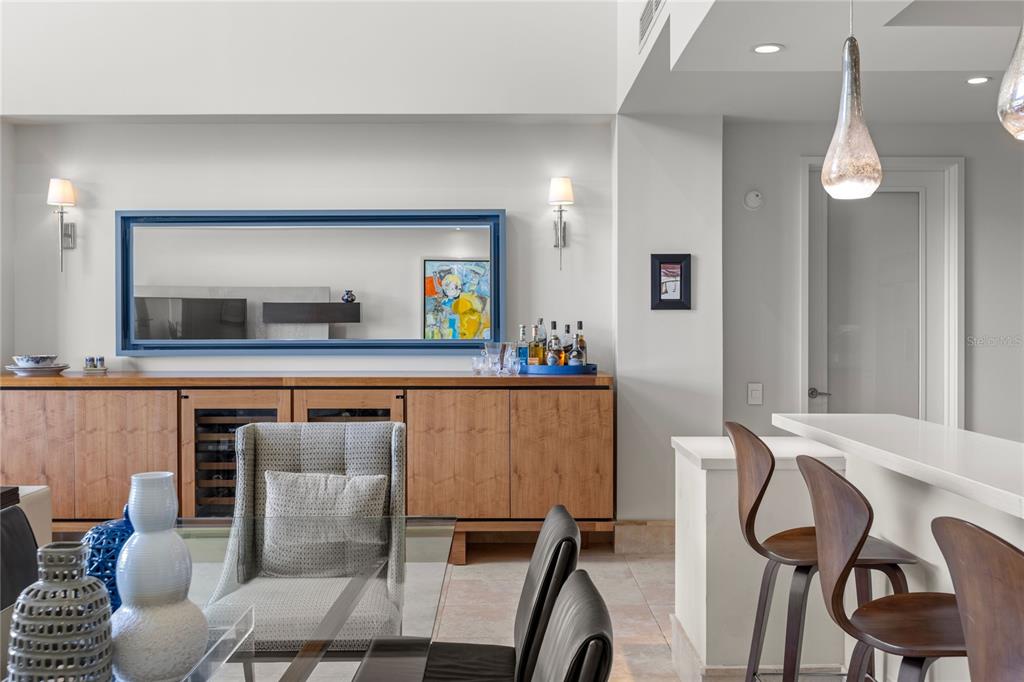 A dining area features a wooden sideboard, a large mirror, and a breakfast bar with stools — 500 PLANTATION DRIVE UNIT 3-202, DORADO, PR