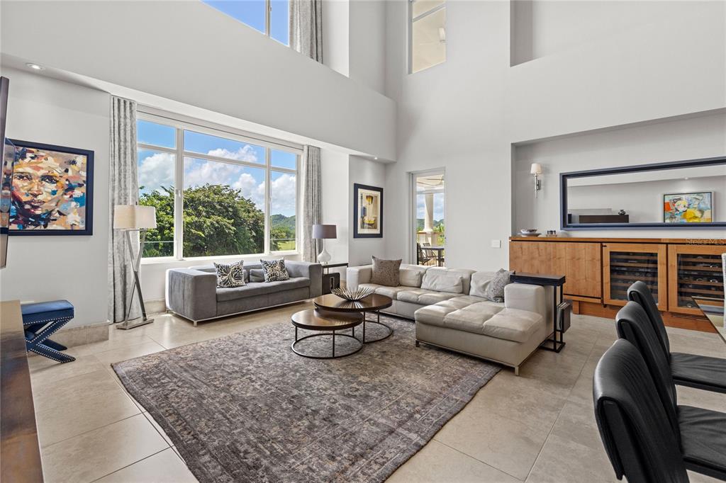 A spacious, high-ceilinged living room with a large sectional sofa, area rug, and floor-to-ceiling windows — 500 PLANTATION DRIVE UNIT 3-202, DORADO, PR