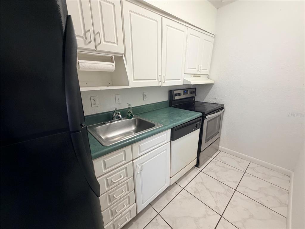 A kitchen features white cabinets, a green countertop, a stainless steel sink, and black appliances — 738 RIDENHOUR CIRCLE UNIT L, ORLANDO, FL