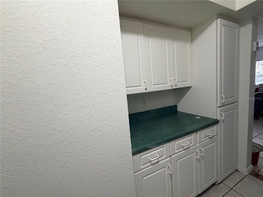 A kitchen nook features white cabinets, a green laminate countertop, and white tile flooring — 738 RIDENHOUR CIRCLE UNIT L, ORLANDO, FL