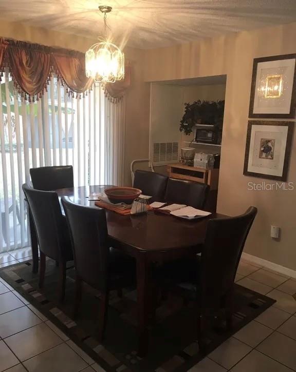 A dining room features a dark wood table, six chairs, and a chandelier on tile flooring — 634 STEAMBOAT COURT UNIT 167, ALTAMONTE SPRINGS, FL