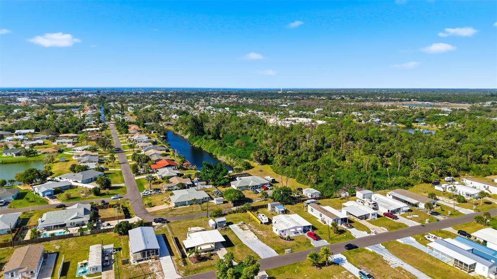 An aerial view shows a residential neighborhood with houses, streets, and a small canal — 1372 IBIS DRIVE, ENGLEWOOD, FL