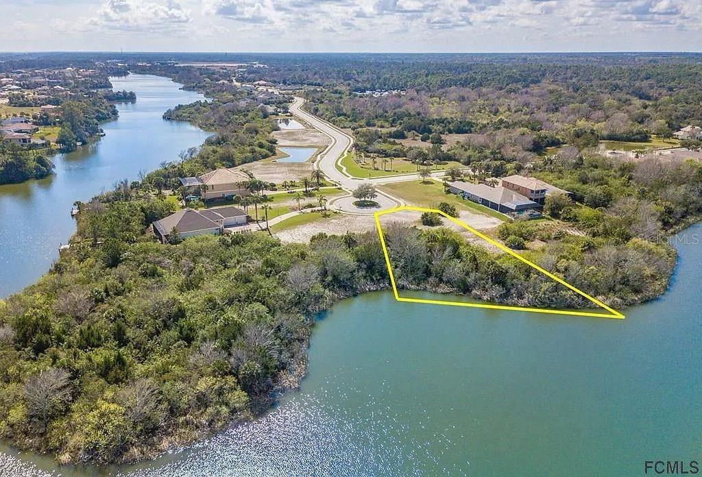 An aerial view shows a waterfront vacant lot outlined in yellow near a residential street — 151 N LAKEWALK DRIVE, PALM COAST, FL