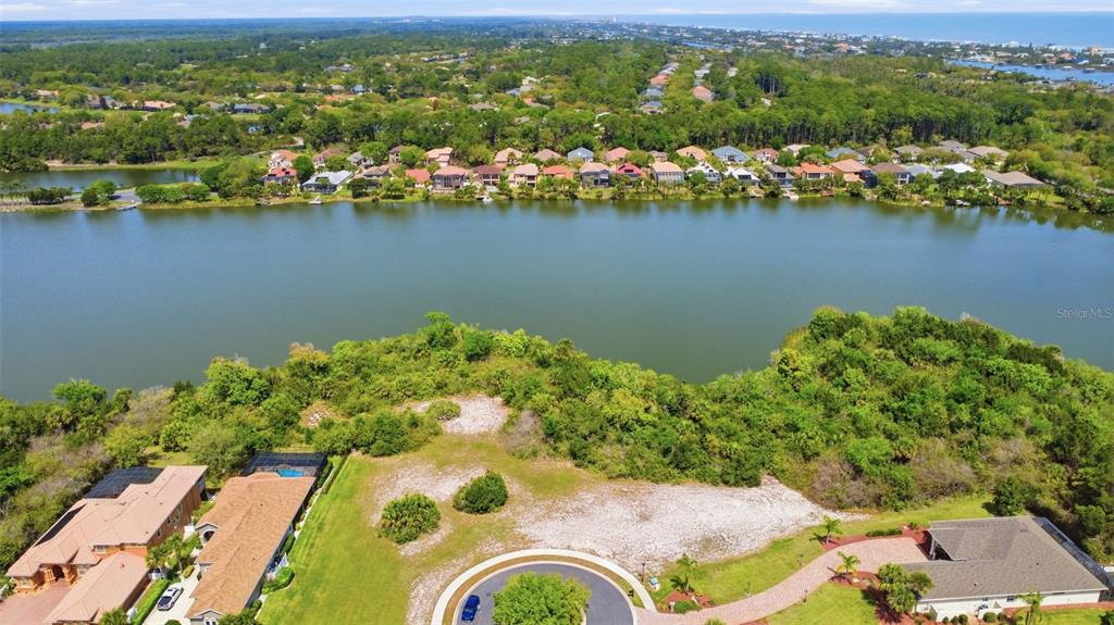 An aerial view shows a vacant lot near a lake surrounded by residential houses — 151 N LAKEWALK DRIVE, PALM COAST, FL