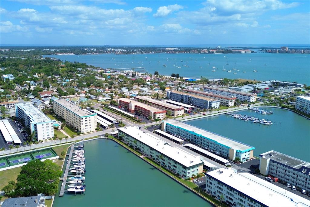 An aerial view shows multiple apartment complexes, a marina with docked boats, and a bay — 2960 59TH STREET S UNIT 210, GULFPORT, FL