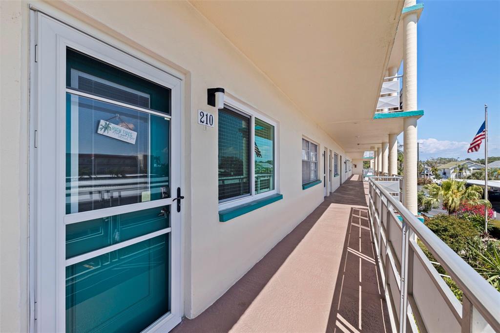 An exterior walkway with a teal door, a window labeled 210, and a metal railing — 2960 59TH STREET S UNIT 210, GULFPORT, FL