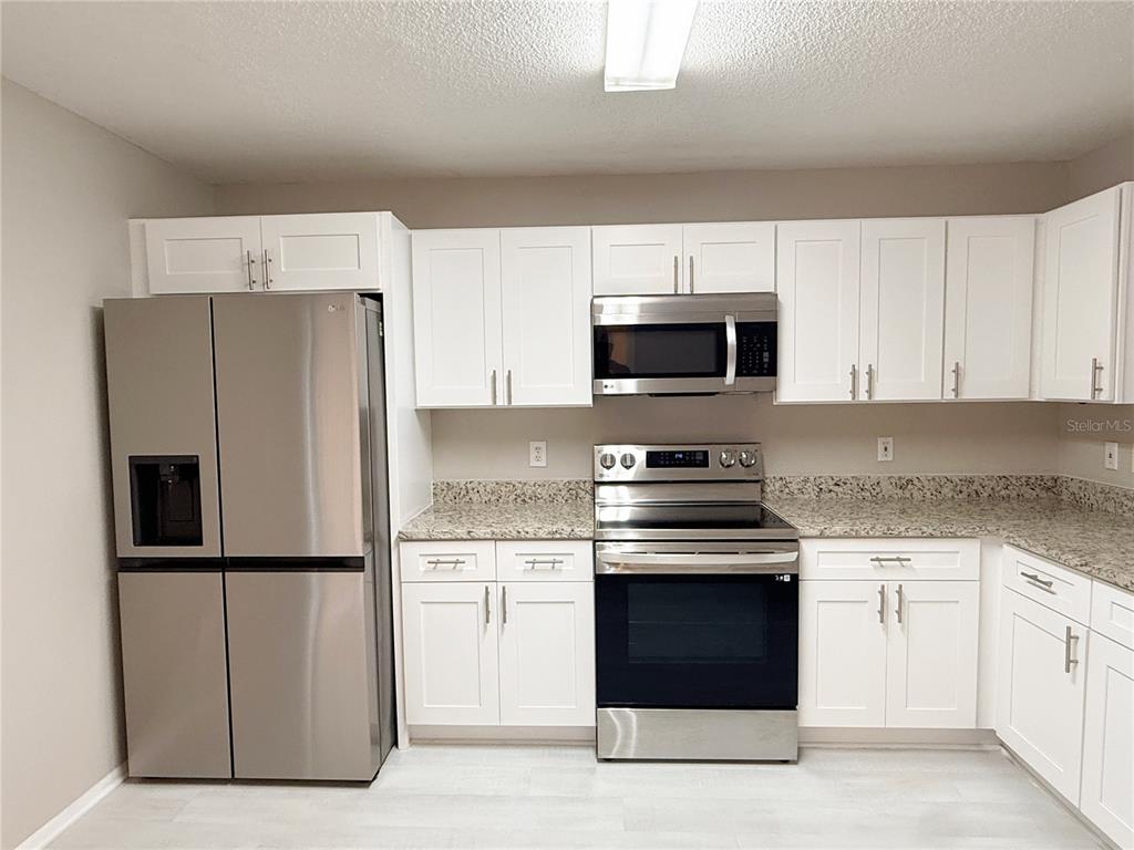 A kitchen featuring white cabinets, stainless steel appliances, and granite countertops — 4417 RIBBLESDALE LANE, ORLANDO, FL