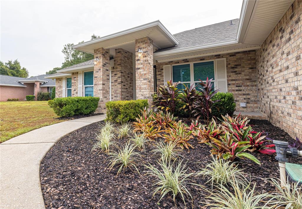 A brick house exterior features a front walkway, landscaped garden beds, and a covered entrance — 6178 SWAINSON STREET, MILTON, FL