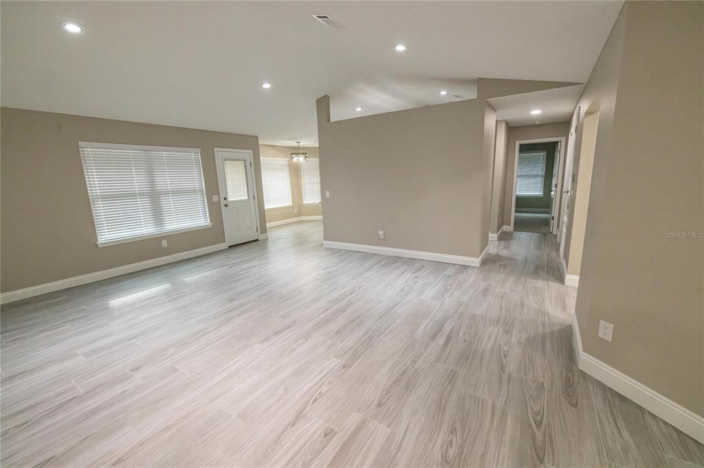 An open-concept living area features light wood-look tile flooring, neutral walls, and recessed lighting — 6178 SWAINSON STREET, MILTON, FL