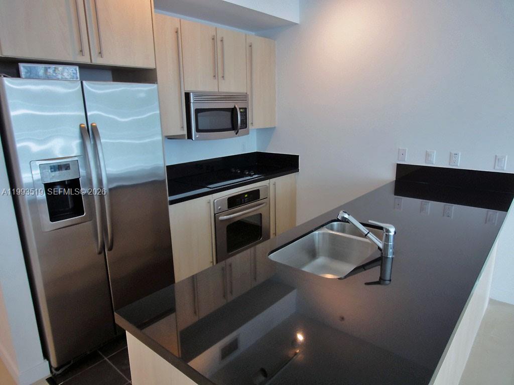 A kitchen features light wood cabinets, stainless steel appliances, and a black countertop island — 1111 SW 1 AV, Miami FL 33130, MIAMI, FL