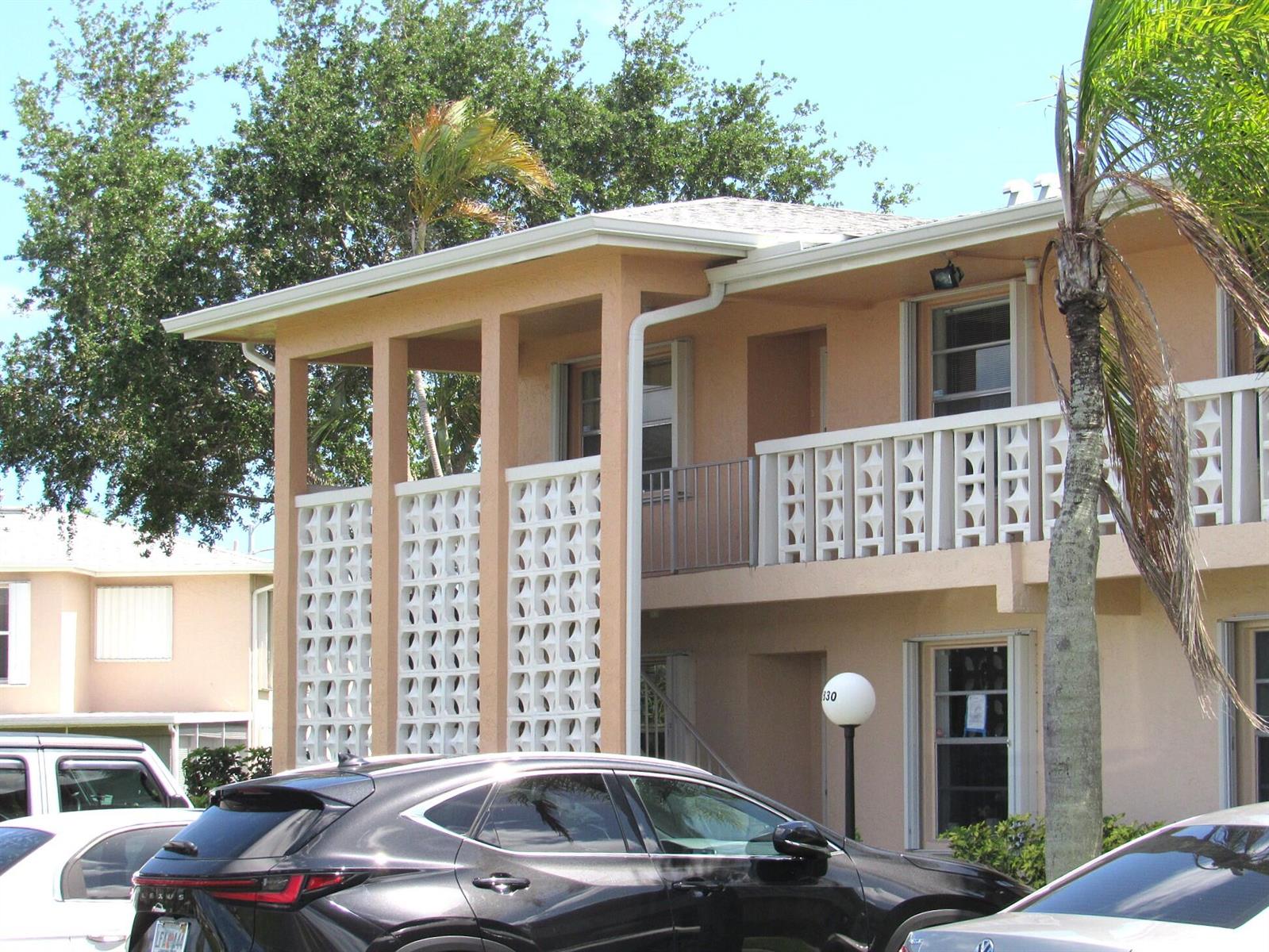A two-story apartment building features peach-colored stucco walls and decorative white concrete screen blocks — 1830 NW 18th Street # 201, Delray Beach FL 33445, DELRAY BEACH, FL