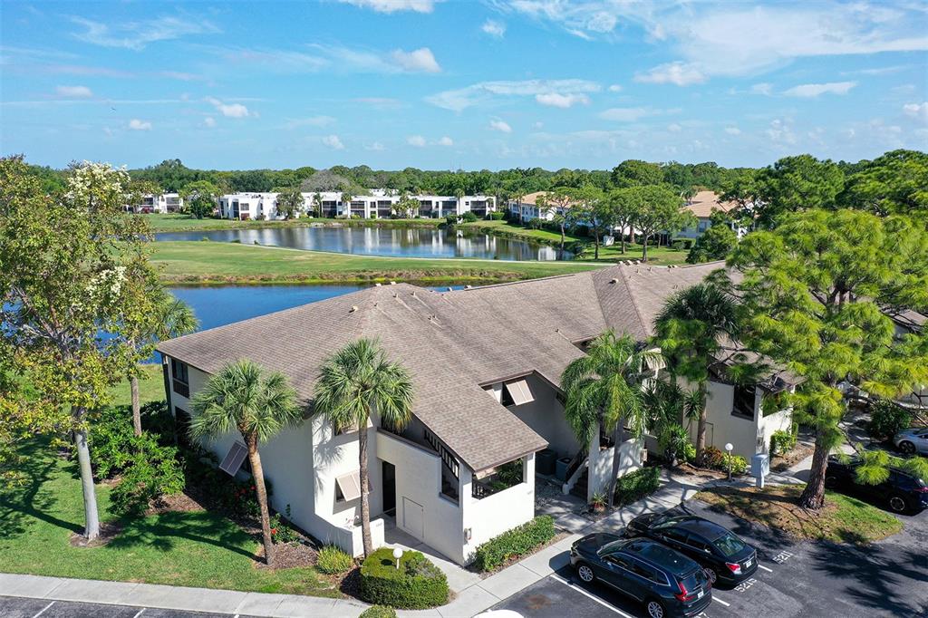 A two-story stucco building features a covered entryway, palm trees, and landscaped shrubbery — 5207 WILLOW LINKS UNIT 34, SARASOTA, FL