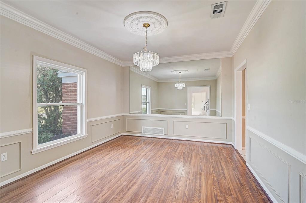 A dining room with wood flooring, a crystal chandelier, and a large wall mirror — 3215 PINE VALLEY DRIVE, SARASOTA, FL