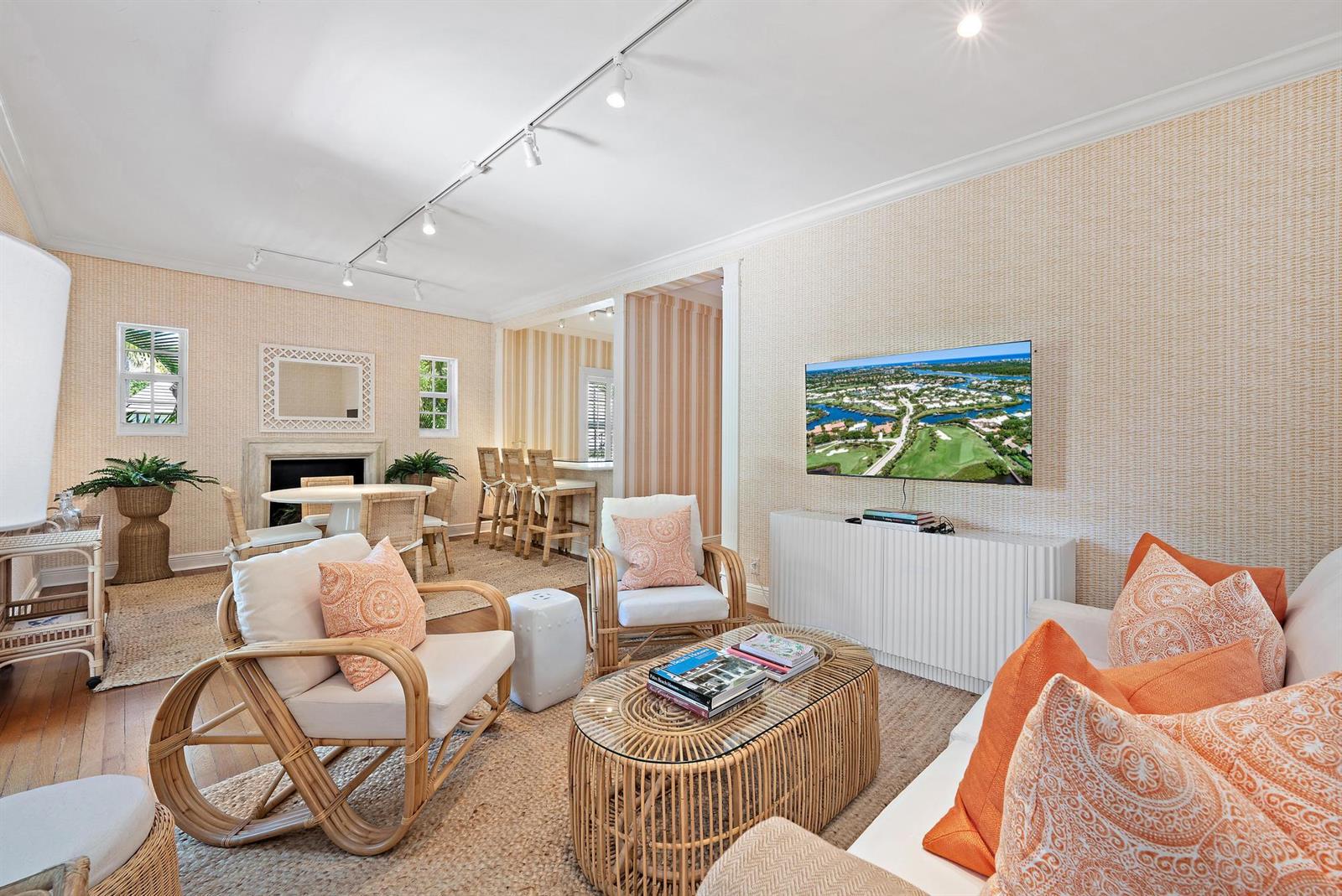 A living room features rattan furniture, a fireplace, a wall-mounted television, and textured wallpaper — 151 S County Road, Palm Beach FL 33480, PALM BEACH, FL