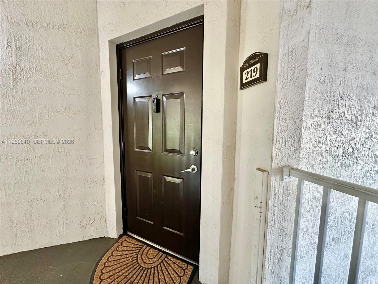 A brown front door with a smart lock is labeled with the number 219 — 11403 NW 89th St # 219, Doral FL 33178, DORAL, FL