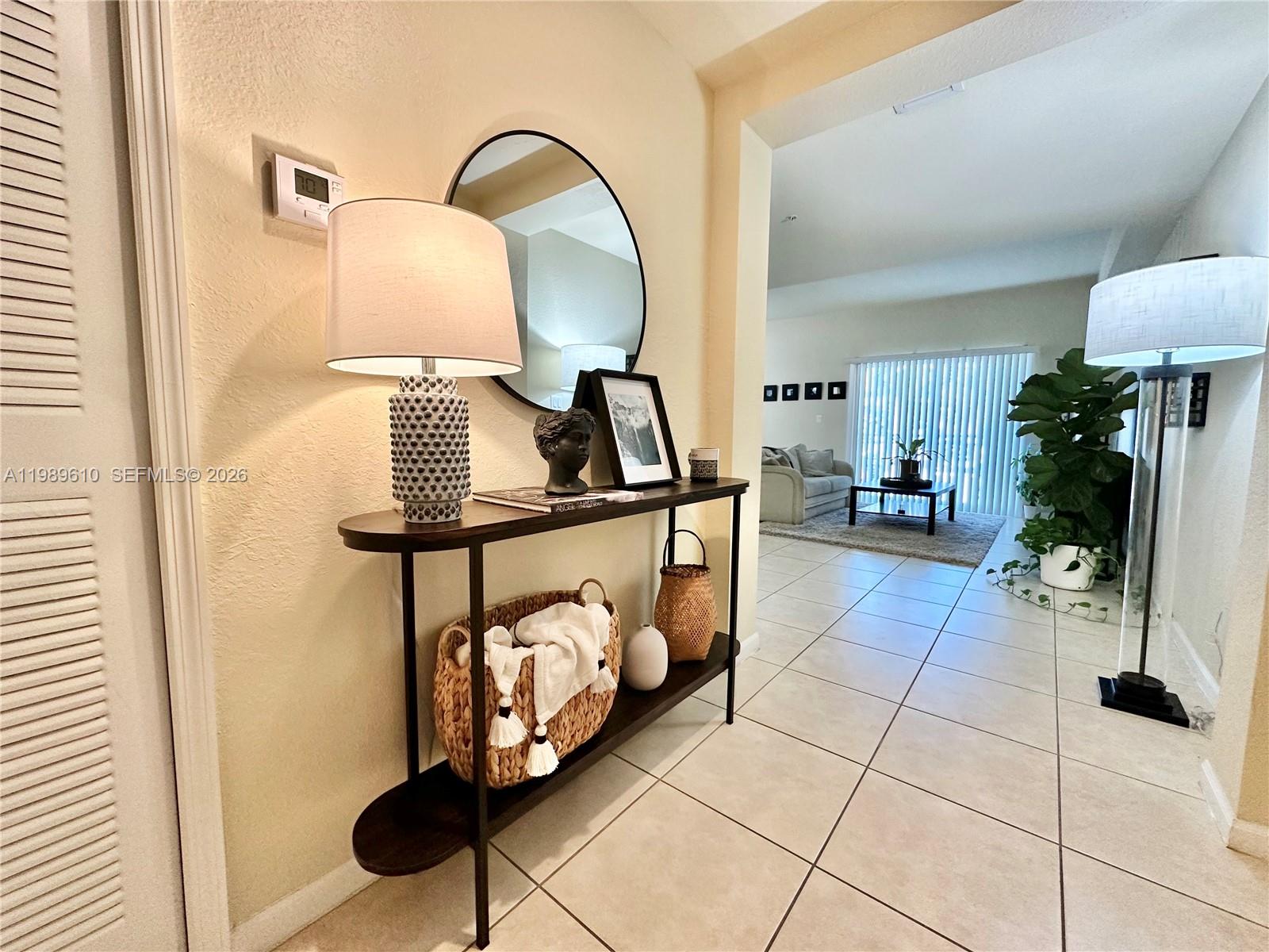 A console table with decor sits in a tiled entryway leading to a living room — 11403 NW 89th St # 219, Doral FL 33178, DORAL, FL