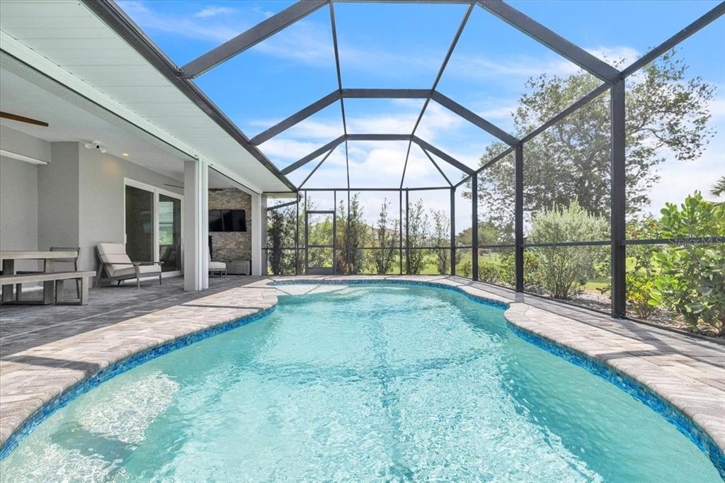A screened-in patio features a swimming pool, stone pavers, and a covered outdoor living area — 26251 COPIAPO CIRCLE, PUNTA GORDA, FL