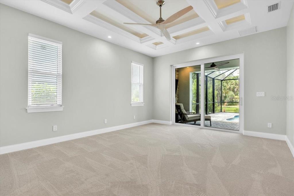 A carpeted bedroom features a tray ceiling, a ceiling fan, and sliding glass doors — 26251 COPIAPO CIRCLE, PUNTA GORDA, FL