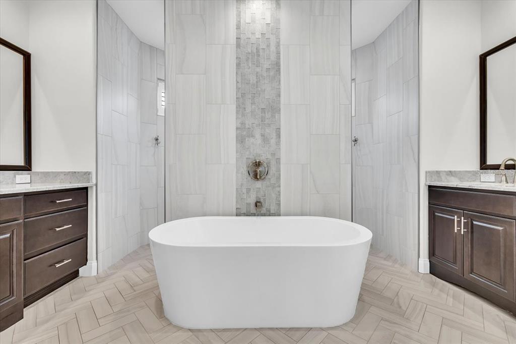 A modern bathroom features a freestanding white tub centered against a tiled accent wall — 26251 COPIAPO CIRCLE, PUNTA GORDA, FL