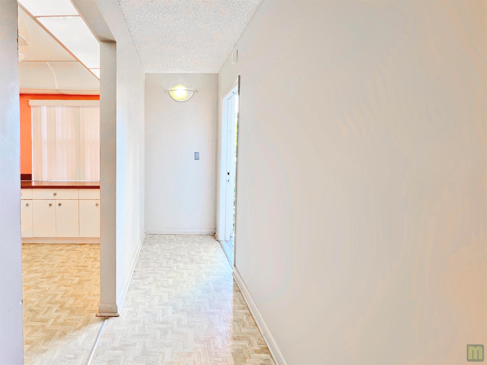 A hallway with patterned flooring leads to a kitchen with white cabinets and orange walls — 1901 Bermuda Circle # M2, Coconut Creek FL 33066, COCONUT CREEK, FL