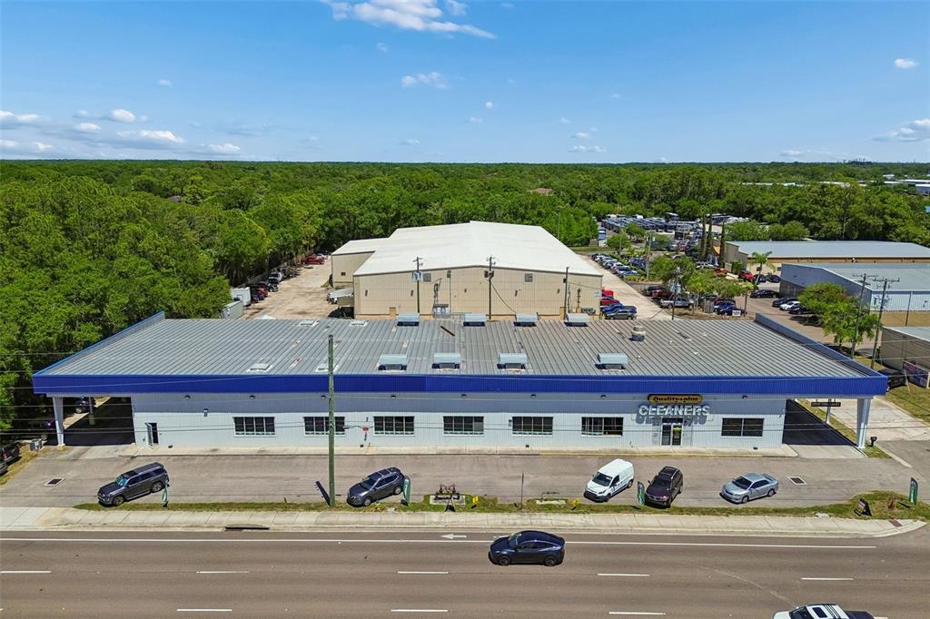 An aerial view shows a commercial building with a blue roof and a parking lot — 9945 RACE TRACK ROAD, TAMPA, FL