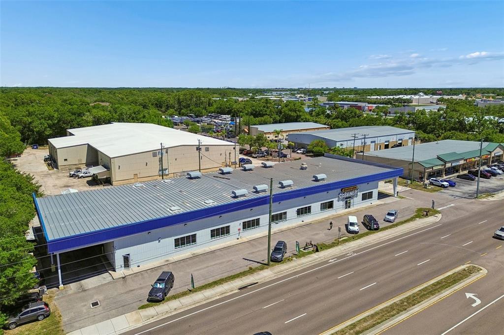 An aerial view shows a commercial building with a blue roof and a parking lot — 9945 RACE TRACK ROAD, TAMPA, FL