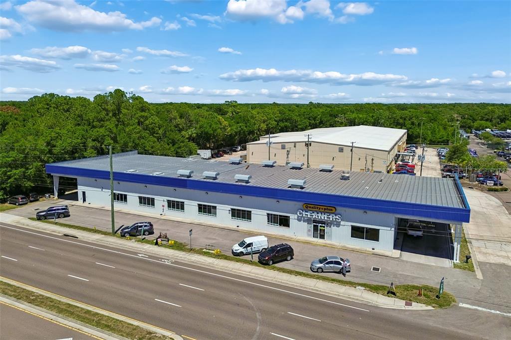 An aerial view shows a commercial building with a blue roof and a parking lot — 9945 RACE TRACK ROAD, TAMPA, FL