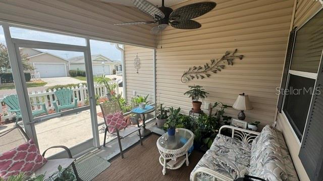 A screened-in porch features a ceiling fan, wicker furniture, potted plants, and a view of houses — 2029 FAIRVIEW LANE, THE VILLAGES, FL
