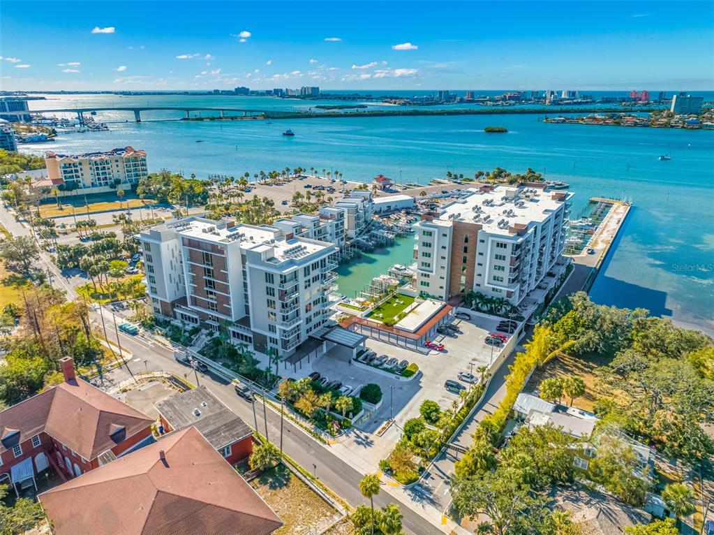 An aerial view shows two modern waterfront apartment buildings with a marina and parking lot — 900 N OSCEOLA UNIT 603, CLEARWATER, FL