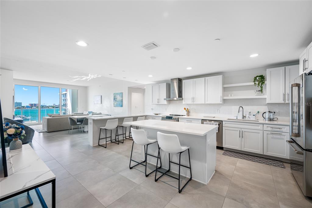 A modern open-concept kitchen with white cabinetry, a central island, and a waterfront view — 900 N OSCEOLA UNIT 603, CLEARWATER, FL
