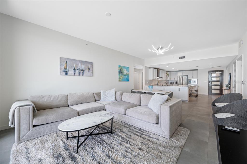 A modern living room with a sectional sofa, marble coffee table, and an open kitchen — 900 N OSCEOLA UNIT 603, CLEARWATER, FL