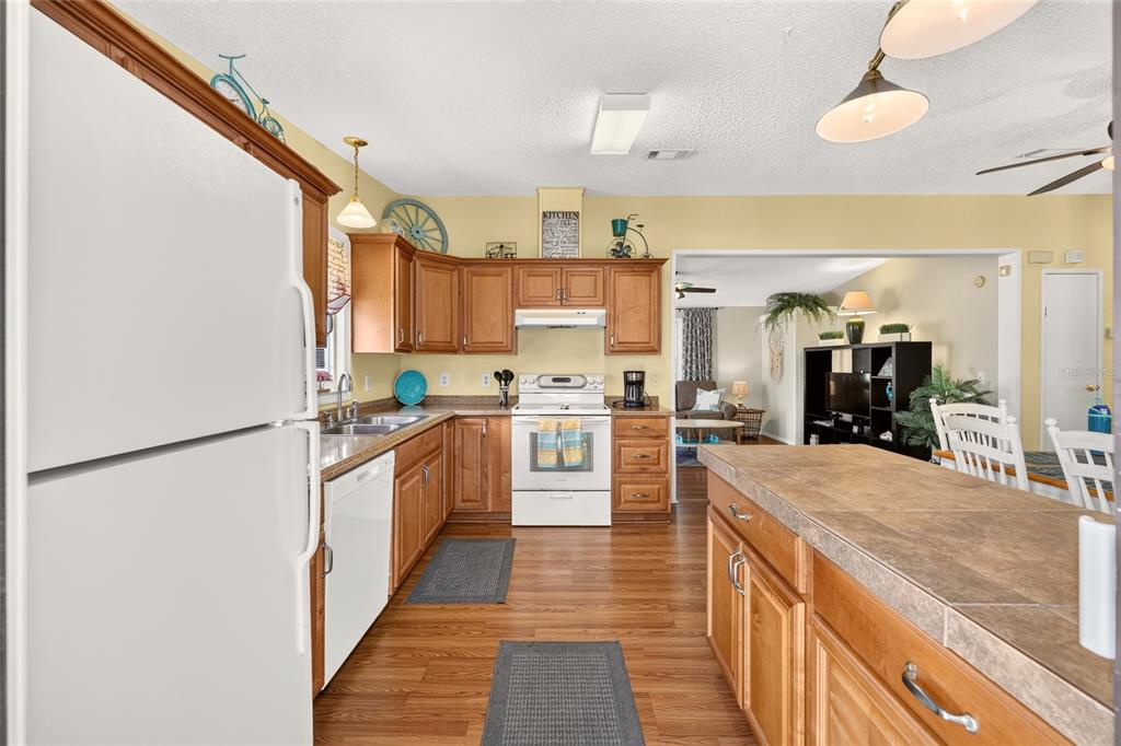 A kitchen with wood cabinets, white appliances, and a tiled island countertop — 1215 PANAMA PLACE, THE VILLAGES, FL