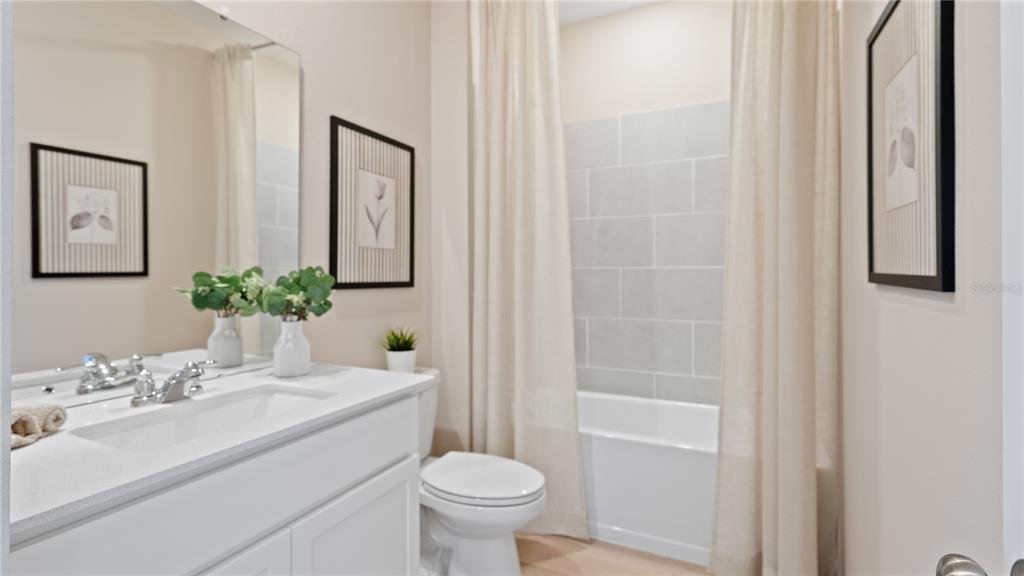 A bathroom features a white vanity, a toilet, and a bathtub with a tiled surround — 4890 WALTHAM FOREST DRIVE, DAVENPORT, FL