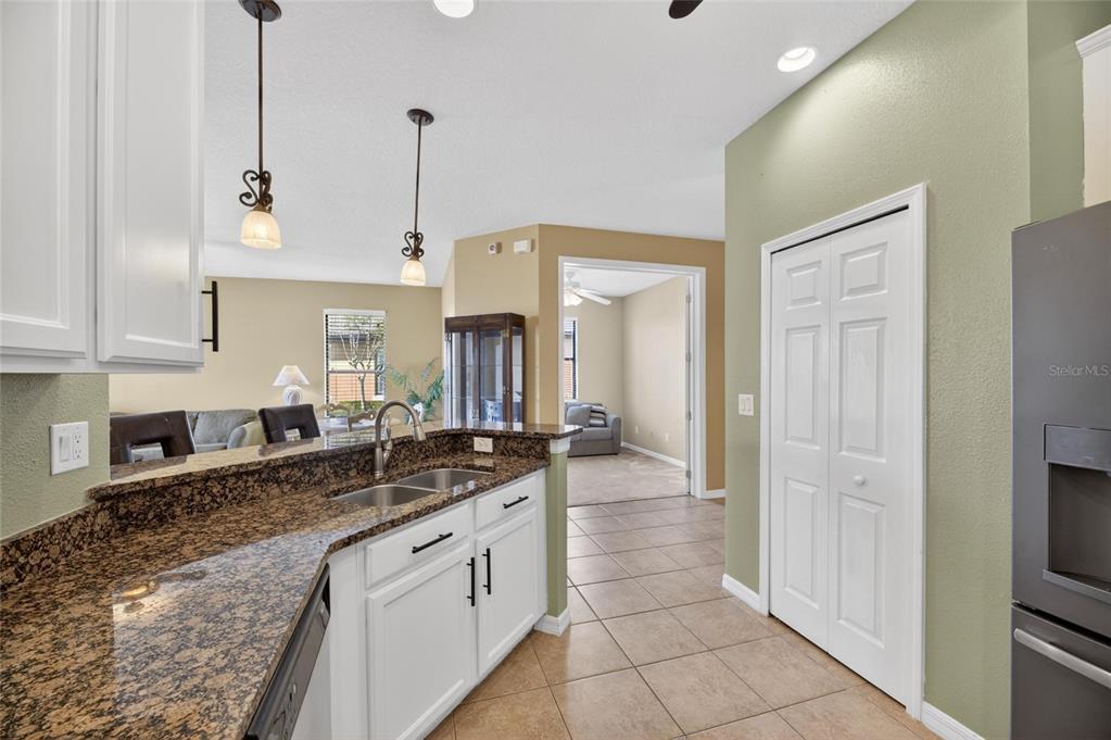 A kitchen with white cabinets, granite countertops, and a tile floor overlooks a living area — 5667 SUNSET FALLS DRIVE, APOLLO BEACH, FL