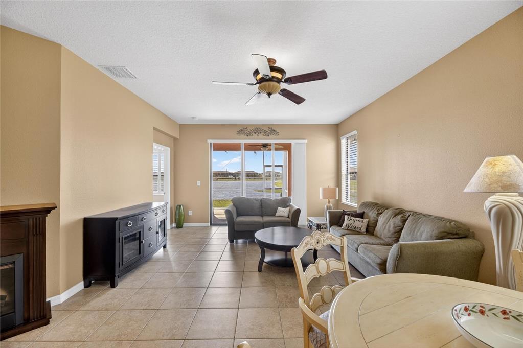 A living room with tile floors, a ceiling fan, and a view of a lake — 5667 SUNSET FALLS DRIVE, APOLLO BEACH, FL