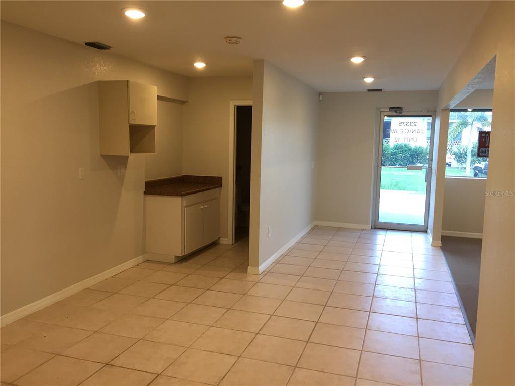 An interior view shows a tiled room with a small kitchenette and an exterior door — 23375 JANICE AVENUE UNIT 12, PUNTA GORDA, FL