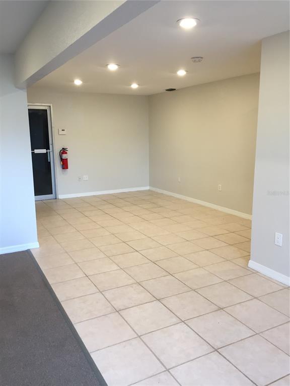 An empty room features light-colored tile flooring, recessed ceiling lights, and a fire extinguisher — 23375 JANICE AVENUE UNIT 12, PUNTA GORDA, FL